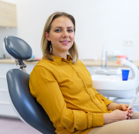 Smiling female patient in dental chair ready for a routine cleaning and exam