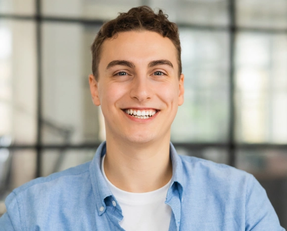 Smiling young man in a blue shirt, representing a patient searching for a dentist"