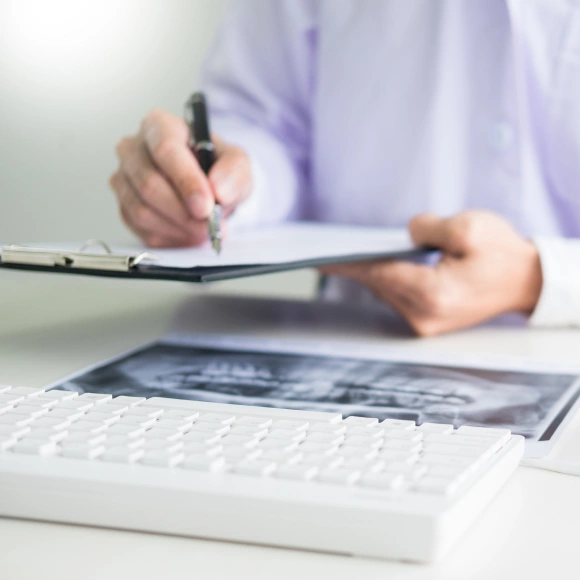 Dentist reviewing a dental X-ray and filling out paperwork for insurance and financing