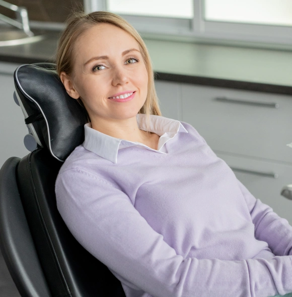 Relaxed female patient smiling in dental chair, welcoming new patients