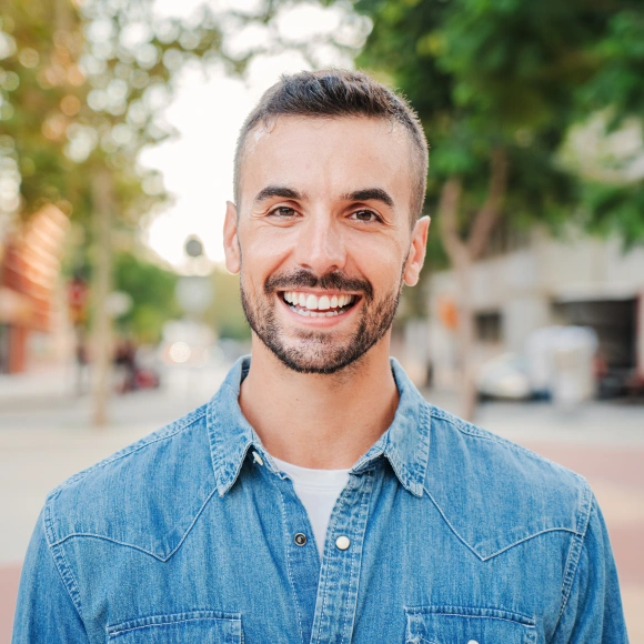 Smiling man outdoors, representing a patient who received restorative dentistry treatment