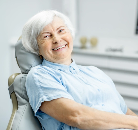 Smiling senior woman relaxing in a dental chair, representing root canal therapy patient care