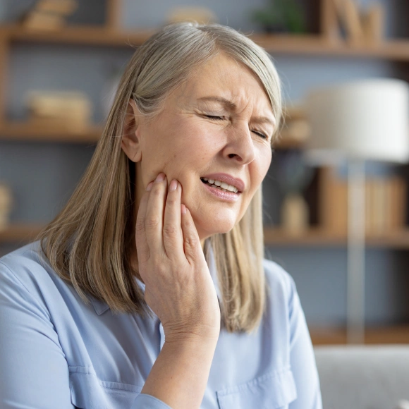Woman holding her jaw in pain, representing TMJ discomfort symptoms